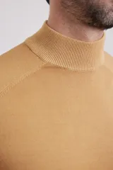 Polera de punto color tostado, de corte ajustado, mangas largas tipo raglán y cuello alto acanalado.