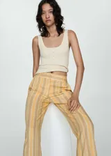 Pantalon de corte recto y tiro medio, confeccionado en tejido mezcla de lino y viscosa con diseño de rayas verticales en tonos amarillos y beige. Cuenta con cierre frontal de cremallera y botón, trabillas para cinturón y bolsillos laterales.