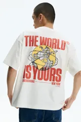 Remera de algodón blanco crudo, de corte oversized con hombros caídos y cuello redondo acanalado. Presenta pequeño estampado en el pecho con la inscripción "nas ©1994" en tono anaranjado.