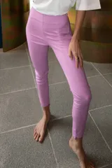 Pantalón largo de ecocuero color lila, con tiro alto, calce ajustado y botamanga irregular.