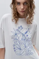 Remera negra de silueta amplia y calce relajado, con cuello redondo, mangas cortas con hombros caídos y estampa botánica en líneas blancas en el frente.