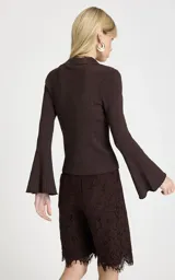 Sweater de punto color marrón, con cuello polo, escote en V profundo y mangas largas con puños acampanados. Presenta un diseño de tejido acanalado vertical.