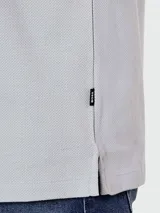 Remera de manga corta, color gris claro, con cuello redondo y un pequeño logo bordado en el pecho.