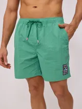 Short de baño color azul, con cintura elástica y cordón ajustable. Presenta un parche pequeño con logo en la parte inferior de la pierna.