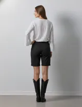 Bermuda de jean color negro, con cierre frontal y botón, bolsillos laterales y diseño clásico de cinco bolsillos.