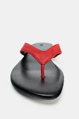 Sandalia plana de piel con diseño de dedo, suela baja y tiras rojas.