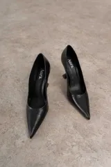 Zapato de tacón negro de cuero, con punta fina y taco con forma geométrica.