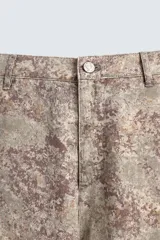 Pantalón de corte relajado confeccionado en tejido ligero de algodón con estampado abstracto de efecto lavado. Presenta cintura elástica, bolsillos frontales y bolsillos traseros de plastrón, con cierre frontal de cremallera y botón.