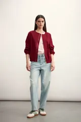 Chaqueta tipo bomber color negro, con cierre frontal metálico, cuello redondo y puños elásticos.