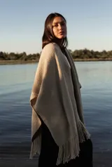 Ruana de lana merino en color tostado, con diseño de punto texturizado y terminación de flecos en el ruedo.