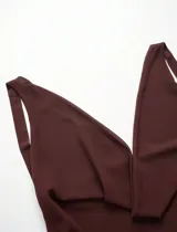 Vestido corto marrón oscuro con escote halter profundo y drapeado tipo cascada en el busto. La falda es corta con capas superpuestas y volados.