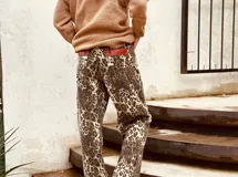 Pantalón de jean con estampado animal print en tonos beige y negro, de corte ancho y tiro medio. Presenta detalles de cuero bordó en la pretina y los bolsillos.