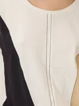 Remera de manga corta con diseño colorblock en tonos blanco, negro y beige, escote redondo y costuras verticales decorativas en el centro.