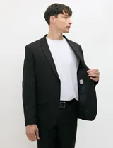 Ambo semi slim de color negro, compuesto por un saco estructurado de dos botones con solapa de muesca tradicional y un pantalón de corte contemporáneo.