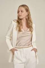 Pantalón de vestir color blanco, de corte recto, con bolsillos laterales y traseros. Se ajusta a la cintura con cinturón de cadena dorada.