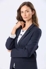 Blazer azul marino de corte clásico con solapa tradicional, cierre frontal con botón y bolsillos con tapa. Presenta un forro interior a rayas en las mangas, diseñado para lucirse al doblarlas.