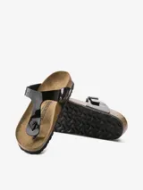 Sandalias Birkenstock modelo Gizeh, color negro charol, con tira delantera ajustable con hebilla metálica y plantilla anatómica de corcho y látex.