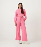 Pantalón tipo pantalona de tiro alto y corte amplio, confeccionado en tejido de ribana texturizada color rosado. Cuenta con cintura elástica y lazo ajustable con detalle de abalorios en los extremos.