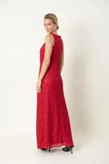 Vestido largo de encaje rojo con brillos, escote cruzado, corte debajo del busto, terminación de blonda y tajo frontal.