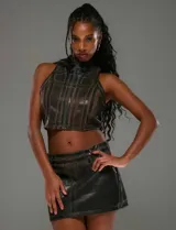 Conjunto de top corto y minifalda color marrón con textura simil cuero y diseño geométrico. El top es sin mangas, con cuello alto y cierre frontal con cremallera. La falda es de corte recto y tiro bajo.