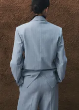 Blazer de corte sastre en color celeste con estampado de raya diplomática, cuello de solapa con muesca, cierre frontal de un botón, bolsillos con solapa en los laterales y bolsillo de ribete en el pecho.