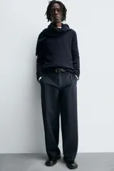 Pantalón de corte balloon fit, color negro, con bolsillos laterales de vivo y bolsillos traseros con solapa. Presenta cierre frontal con cremallera y botón.