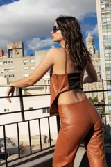 Top de cuero ovino color marrón, con escote recto y breteles finos. Presenta cortes verticales en el frente que estilizan la silueta, cierre lateral metálico y espalda elastizada para un ajuste cómodo.