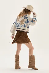 Cardigan de tejido de punto color crudo con diseño de jacquard floreado en tonos azules y marrones. Presenta cuello en V, cierre frontal con botones y ribetes a rayas en cuello, puños y bajo.