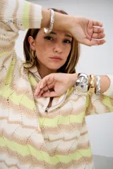 Sweater de punto con cuello alto y cierre frontal, de manga larga y diseño holgado. Presenta un patrón de ondas en colores blanco, beige y verde lima.