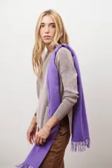 Buzo de tejido de punto en color beige, con cuello redondo, mangas largas y un bolsillo frontal tipo canguro. Presenta un corte holgado con aberturas laterales en el ruedo.