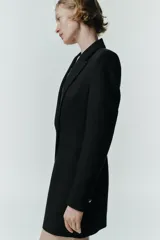 Blazer larga negra con cuello solapa, manga larga y bolsillos de vivo en el delantero. Cierre frontal con dos botones plateados.