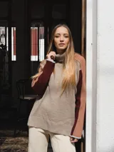 Buzo de tejido de punto con cuello alto, diseño color block en tonos beige, bordó y rosa viejo, con mangas largas y puños en contraste.