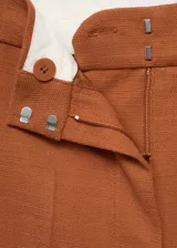 Pantalón de vestir color ladrillo, de tiro alto, corte recto y largo. Confeccionado en tejido mezcla de algodón y lino, con cierre delantero de cremallera, doble gancho y botón interior.