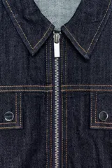 Chaleco de denim oscuro con cuello solapa, cierre frontal con cremallera metálica y bolsillos delanteros con tapeta. Presenta un diseño de corte abullonado con bajo elástico.