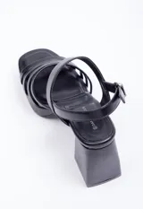 Sandalias plateadas de símil cuero con plataforma y taco cuadrado. Presentan cinco tiras finas sobre el empeine y agarre con hebilla en el tobillo.