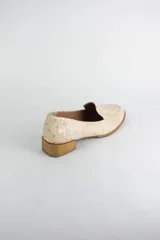 Mocasin de cuero con textura símil avestruz en color suela, con punta redonda y taco bajo cuadrado símil madera.