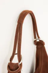 Bolso hobo de cuero gamuzado color marrón, con correa de hombro y cierre superior.