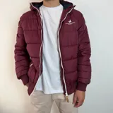 Campera puffer color bordó con capucha, cierre frontal blanco y puños tejidos acanalados. Presenta el logo de la marca Santa Barbara Outfitters bordado en el pecho.