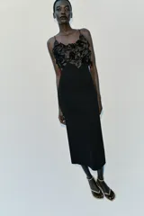 Vestido midi negro de punto con tirantes finos, escote recto adornado con aplicaciones de flores tridimensionales de tela satinada y abertura en la espalda.