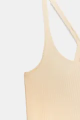 Camiseta ajustada (slim fit) color beige claro, con escote redondo y tirantes finos que se cruzan en la espalda.