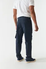 Pantalón cargo verde militar sin puños, de corte recto, con bolsillos laterales y traseros. Se ajusta a la cintura con cinturón de cuero marrón.