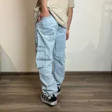 Pantalón jean cargo gris con efecto lavado, corte recto y bolsillos laterales.