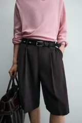 Bermuda negra de corte ancho (wide fit) confeccionada en tejido con mezcla de viscosa. Presenta pliegues en el delantero, bolsillos frontales y bolsillos de vivo en la parte trasera. Cierre frontal con cremallera y gancho metálico oculto.