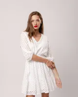 Vestido corto negro de broderie de algodón, con escote en V, mangas tres cuartos, cintura elastizada, falda corte A con volado y forro interior.