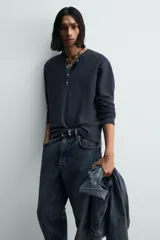 Camiseta de manga larga para hombre con corte relajado, confeccionada en tejido con estructura waffle. Presenta un cuello redondo tipo panadero con cierre frontal de botones a presión.