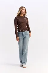 Jean de corte recto y tiro medio, confeccionado en denim de tono azul claro con acabado lavado. Presenta cierre frontal con botón y cremallera, además de bolsillos laterales y traseros.