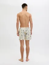 Short de baño de tiro medio con estampado botánico abstracto en tonos blanco, negro y amarillo sobre base color crema. Cuenta con cintura elástica con cordón ajustable, bolsillos laterales y bolsillo trasero.
