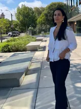 Camisa azul marino de manga larga con cuello camisero y cierre de botones. Presenta volantes horizontales en la parte delantera.