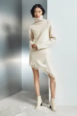 Jersey de punto liso confeccionado con lana, con cuello subido, manga larga y acabados en rib.