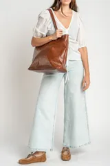 Blusa marrón de algodón con bordados sutiles, escote en V, mangas cortas abullonadas y detalle de fruncido con cordón ajustable en el centro del frente.